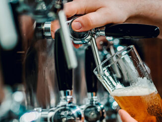 A bartender pours a pint of beer in a craft brewery's taproom.