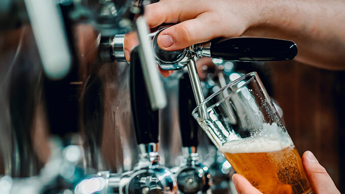 A bartender pours a pint of beer in a craft brewery's taproom.