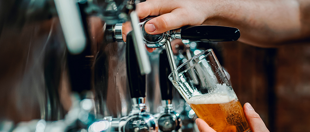 A bartender pours a pint of beer in a craft brewery's taproom.