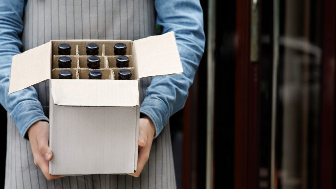 Beer for party at weekend. Bartender holds open cardboard box with bottles